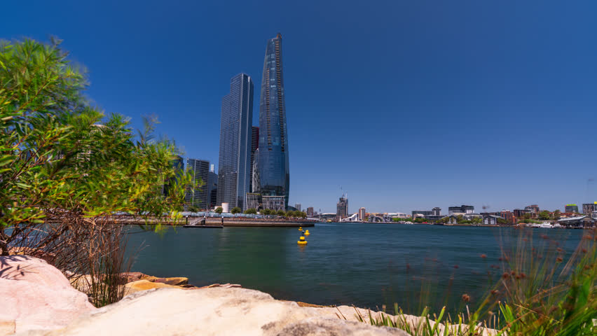 Timelapse of a modern Skyscraper in Darling Harbour, Sydney, Australia with the rocks and water in front