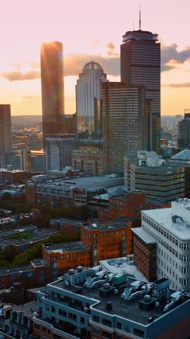 Dynamic drone movement over Boston skyline during golden hour sunset. Beautiful urban landscape with historic brick buildings and modern glass skyscrapers in Massachusetts cityscape footage.