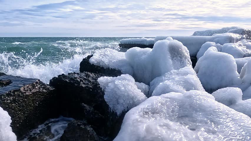 Coastal cliffs and shoreline protection structures covered with a thick layer of ice formed by freezing saline sea spray during a winter storm, Black Sea coast, Odessa, Ukraine