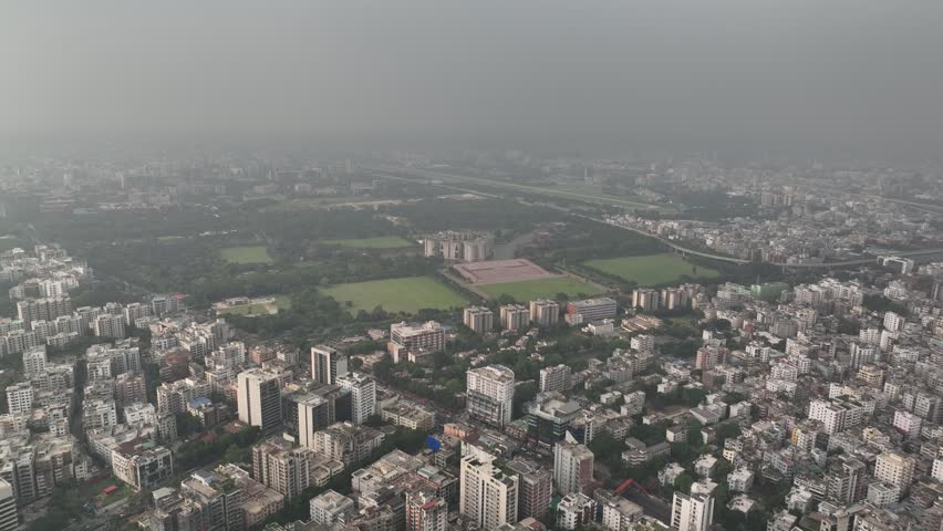 High angle panoramic view of dhaka, the capital of bangladesh, showing a sprawling cityscape with lush green parks, urban development, and the iconic national parliament house complex