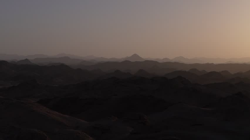 Mystical panorama of the marsa alam desert landscape in egypt as the sun rises over the hazy, layered mountains, casting a beautiful golden light across the serene and tranquil scene