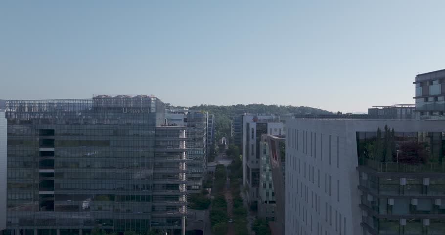 High-angle aerial drone shot of the modern corporate office buildings and green parks in Pangyo Techno Valley, Seongnam, South Korea, captured during a clear morning.