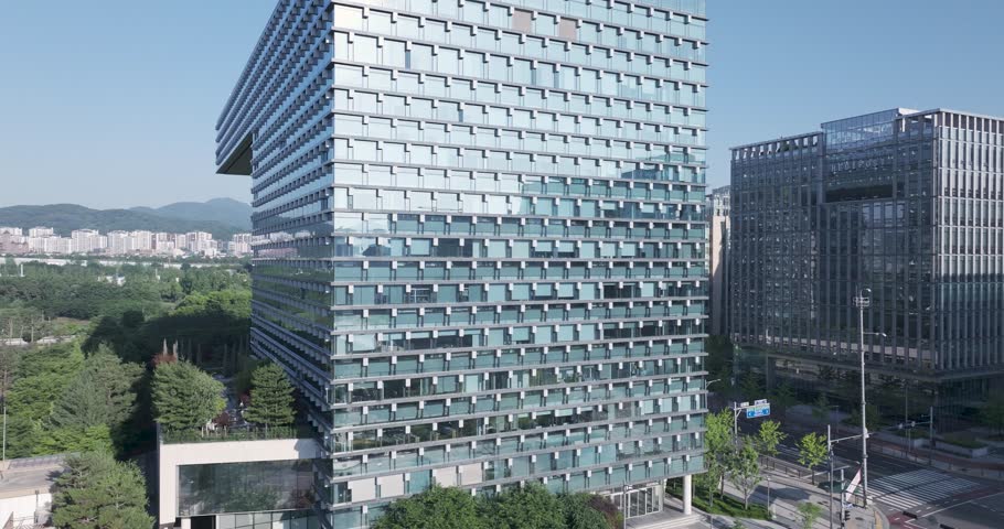 High-angle aerial drone shot of the modern corporate office buildings and green parks in Pangyo Techno Valley, Seongnam, South Korea, captured during a clear morning.