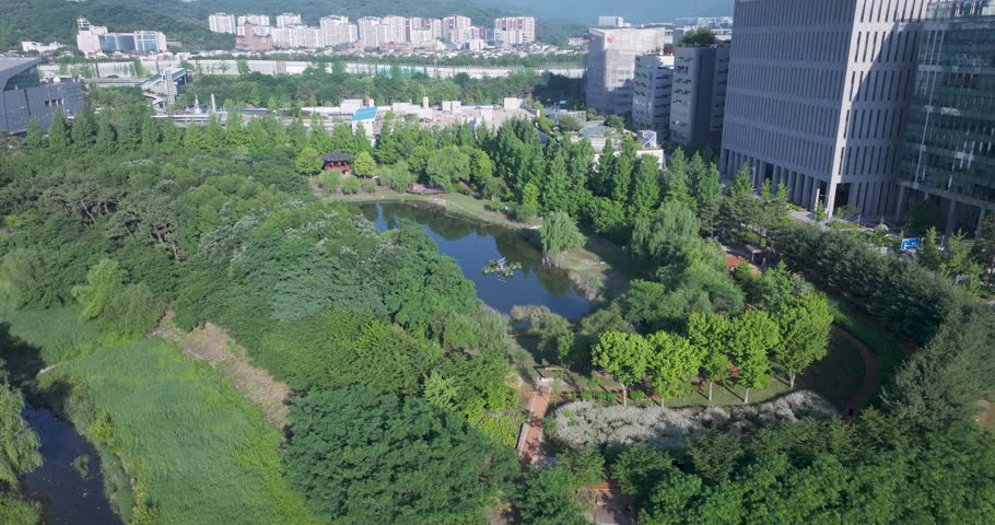 High-angle aerial drone shot of the modern corporate office buildings and green parks in Pangyo Techno Valley, Seongnam, South Korea, captured during a clear morning.