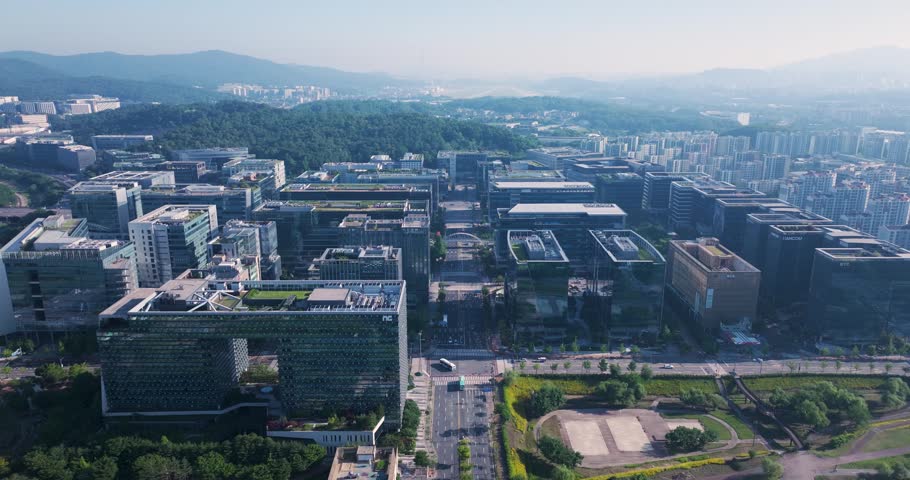 High-angle aerial drone shot of the modern corporate office buildings and green parks in Pangyo Techno Valley, Seongnam, South Korea, captured during a clear morning.