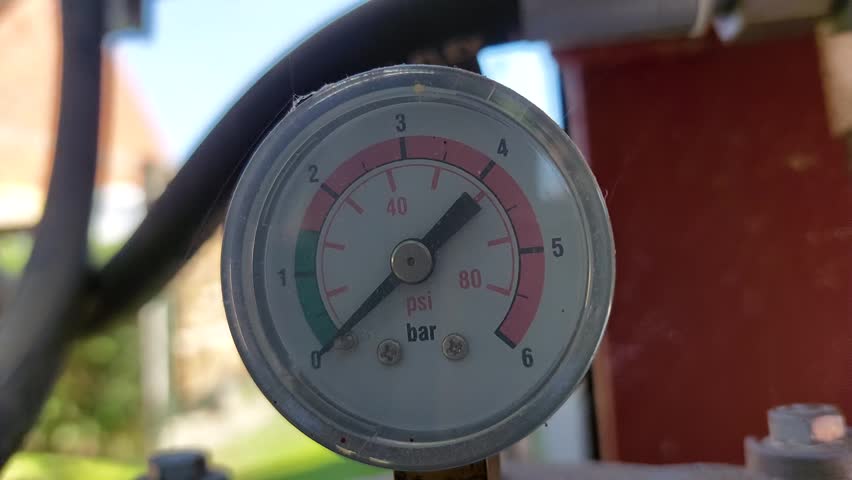 Worker checking an industrial pressure gauge manometer showing bar and psi