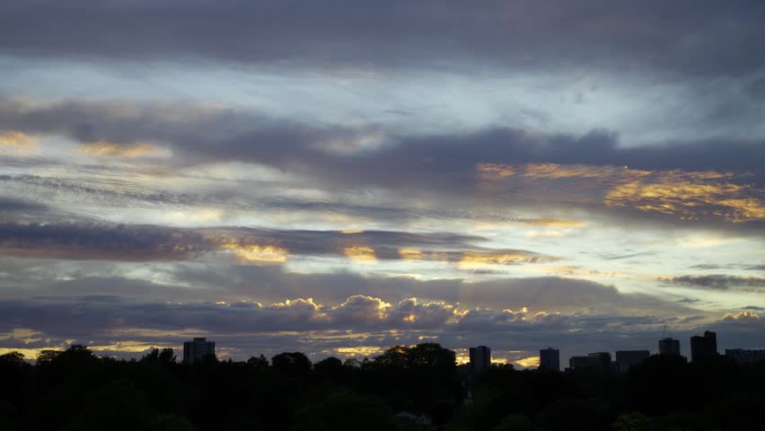 Timelapse with Dramatic Multi-Layered Clouds over Birmingham Skyline.
A wide-angle timelapse capturing the transition of a sunset over a Birmingham skyline. The sky features intricate layers of dark, rippling altocumulus clouds contrasting against a vibrant horizon of orange and gold light. Below, the dark silhouettes of city buildings and trees create a moody urban atmosphere. Perfect for projects needing a sense of time passing, weather transitions, or a peaceful evening backdrop.
