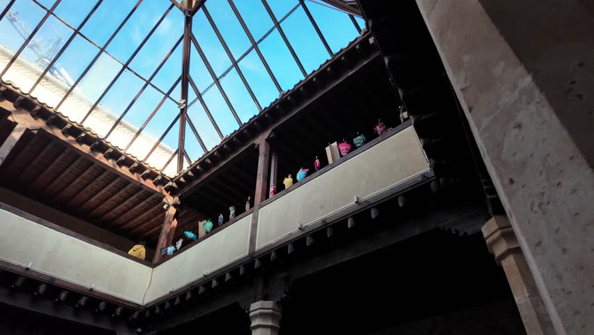 A smooth camera pan captures the contrast between traditional Spanish balconies and a contemporary glass roof within a restored historic patio in Castile and Leon.