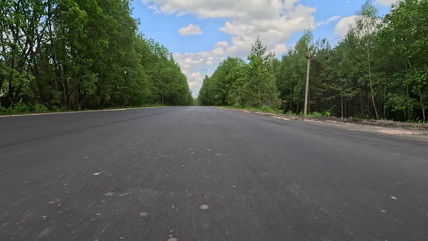 Driving a red car over the road along the asphalt at speed, view from the wheel in motion.