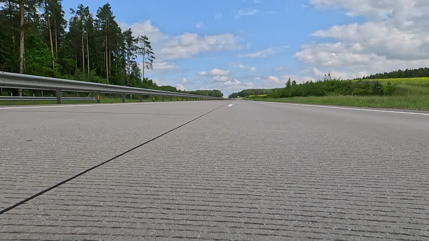 Driving a red car over the road along the asphalt at speed, view from the wheel in motion.