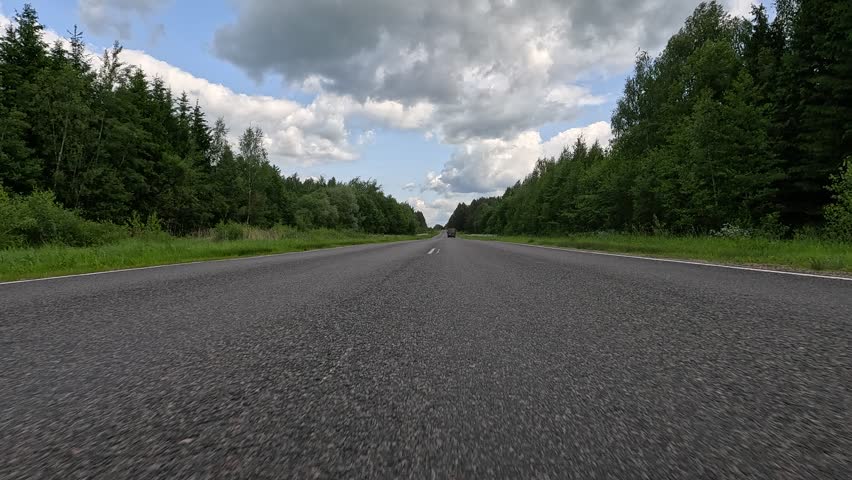Driving a red car over the road along the asphalt at speed, view from the wheel in motion.