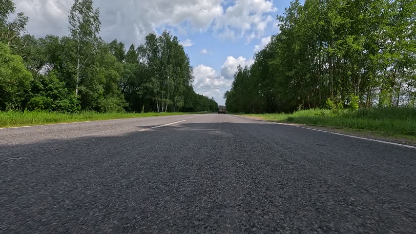 Driving a red car over the road along the asphalt at speed, view from the wheel in motion.