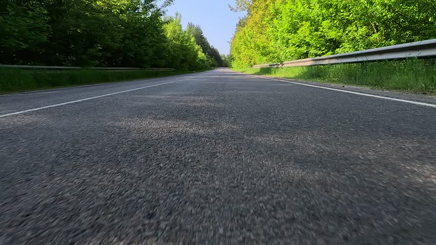 Driving a red car over the road along the asphalt at speed, view from the wheel in motion.