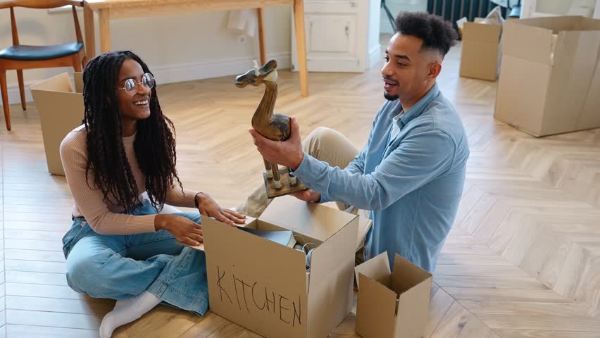 A man hands a statuette to a woman sitting next to him, they talk while he takes a book out of the box
