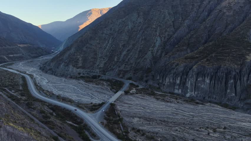 Stunning drone shot of a scenic highway crossing a rugged mountain canyon in a remote rural area.