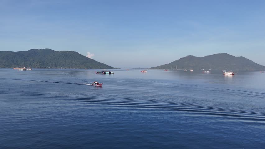 Small fishing boat moving across the calm blue ocean