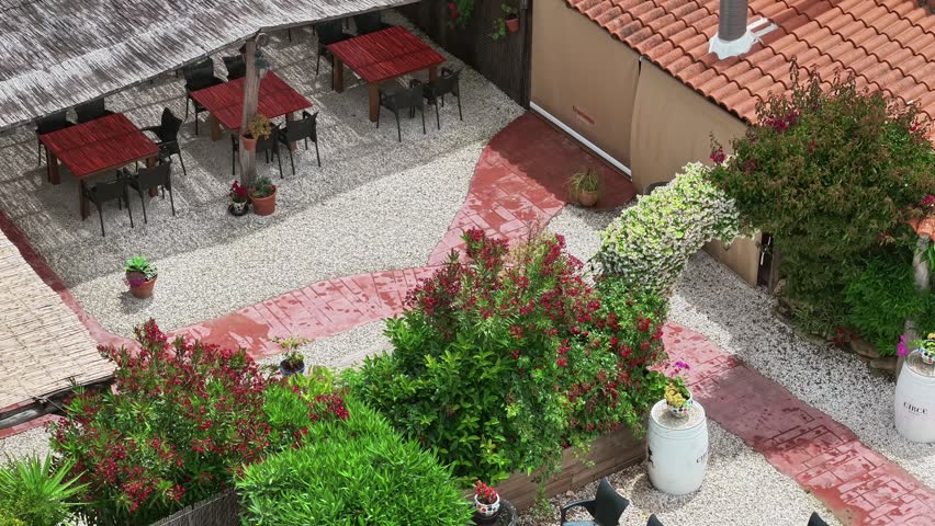 Aerial view showing an outdoor restaurant terrace with dining tables and lush greenery in Cadiz. pull back shot