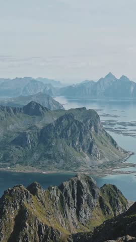Majestic drone flyover across a dense green forest revealing a serene blue lake with layered mountain peaks under clear sky