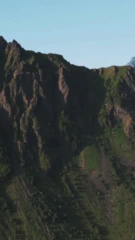 Group of hikers sitting on a rocky mountain summit enjoying the panoramic view of blue ocean water and distant islands