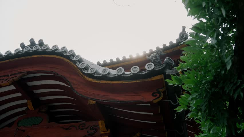 Close-up upward view of ornate Japanese temple roof with red and gold carvings