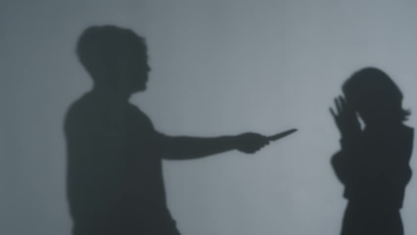 Silhouette of a man holding a knife to a woman