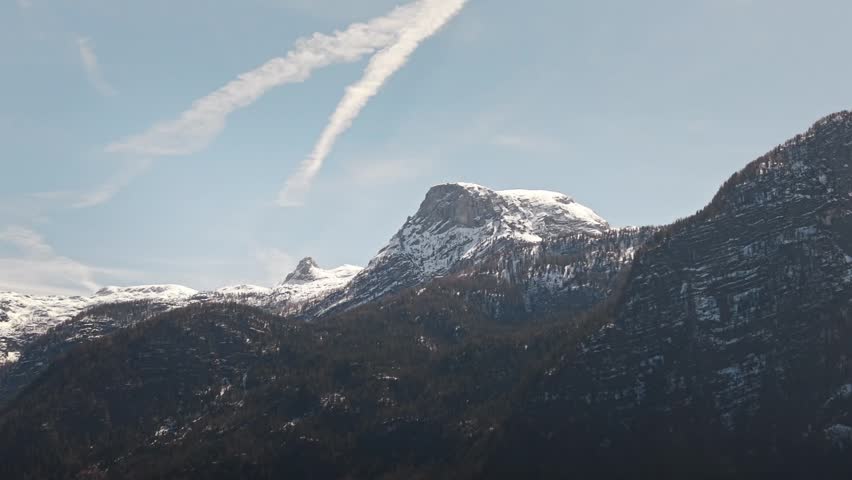 Wide mountain landscape in Banff National Park Alberta Canada featuring snow covered Mount Rundle beneath blue sky with wispy clouds above rugged peaks