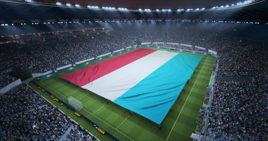 Professional Stadium Soccer Game Championship With Flag of Luxembourg Spread Across the Pitch Before Football Match Start. Cheering Crowds of Fans Surround the Field. Aerial Elevated Static Wide Shot
