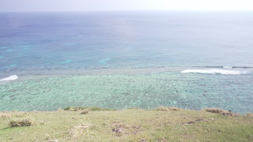 Breathtaking high angle view of the vast emerald green and deep blue ocean seen from a grassy cliff, Yonaguni Island, Japan