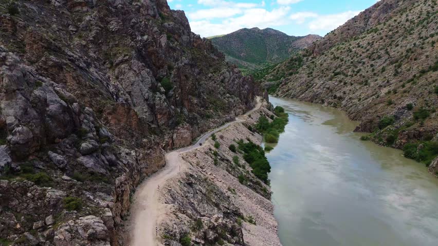 Aerial view of the historic Kemaliye Stone Road winding through the dramatic Karanlik Canyon next to the Euphrates River. Famous rocky gorge, wilderness travel and tourism in Turkey.