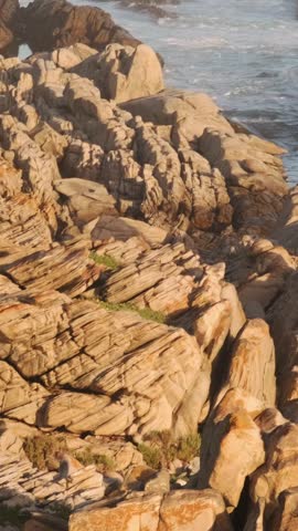 Rocky coastal formation with ocean waves washing over stones, scenic natural landscape showing rugged shoreline, marine environment and travel destination