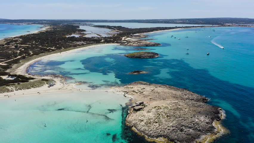 Aerial view of Ses Illetes beach in Formentera, Spain. Turquoise Mediterranean waters and white sandy shoreline within Ses Salines Natural Park, iconic Balearic paradise destination with crystal clear sea.