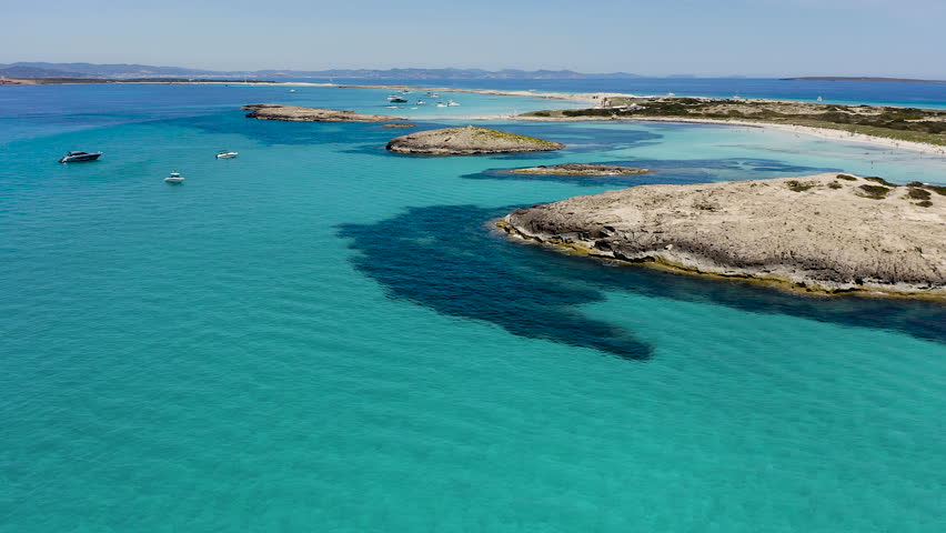 Aerial view of Ses Illetes beach in Formentera, Spain. Turquoise Mediterranean waters and white sandy shoreline within Ses Salines Natural Park, iconic Balearic paradise destination with crystal clear sea.