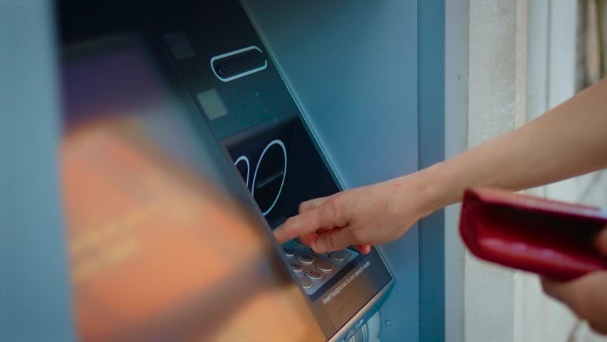 Entering PIN code on outdoor ATM keypad during banking transaction and cash withdrawal. Female hand using automated teller machine for secure financial operation in public location. Digital banking