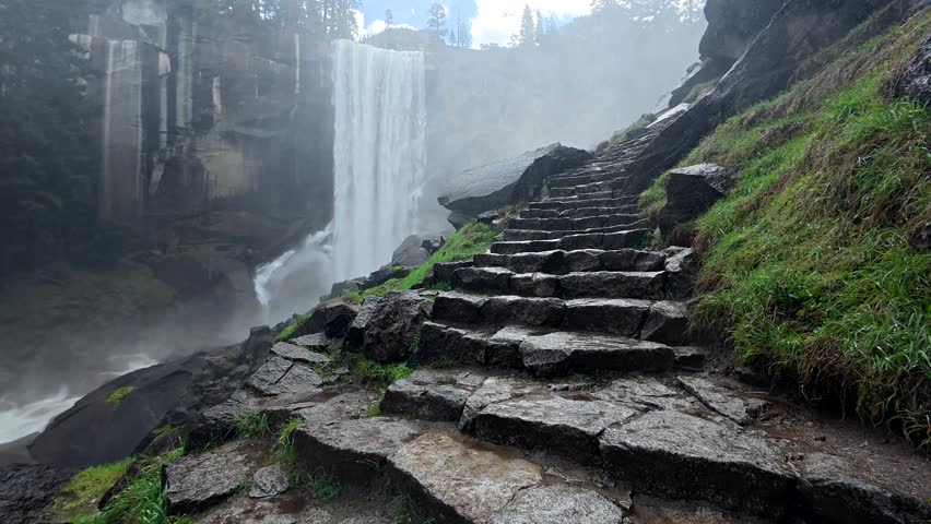 Powerful vernal fall creating a misty atmosphere along the wet stone staircase of the mist trail, a famous hiking path in california