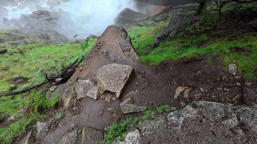 Majestic view of the powerful vernal fall in yosemite national park, with water cascading down the granite cliff face surrounded by mist, lush green trees, and the scenic mist trail