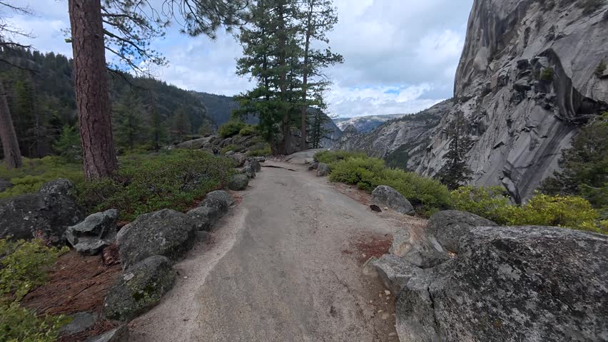 Personal perspective of a person hiking along the rocky mist trail, walking towards the majestic nevada fall and vernal fall in the scenic wilderness of yosemite national park, california