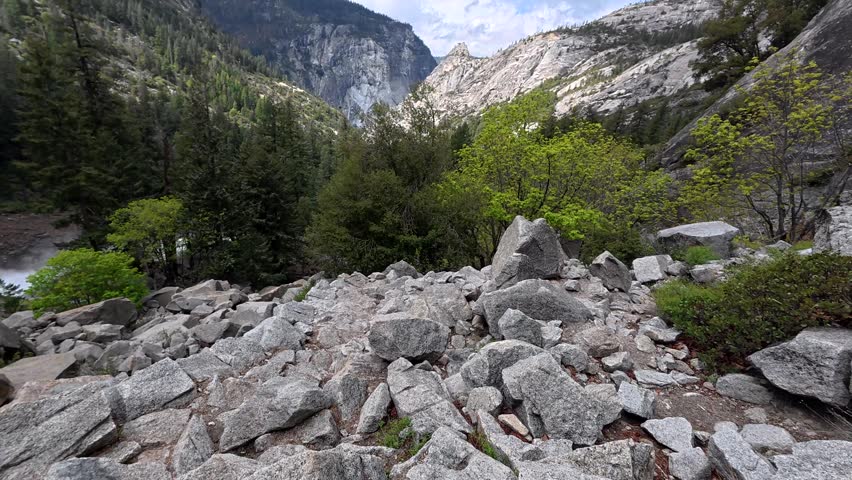 Young male backpacker exploring a difficult rocky path on the mist trail, hiking towards the scenic nevada fall waterfall in the beautiful yosemite national park, california