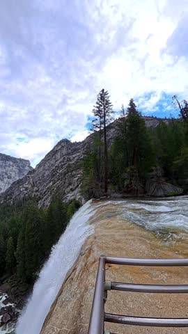 Powerful water from nevada fall cascading over the granite cliff edge along the mist trail, showcasing the immense scale and natural beauty of yosemite national park