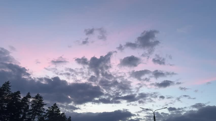 Dramatic twilight sky with dark clouds and tree silhouettes, atmospheric evening landscape.