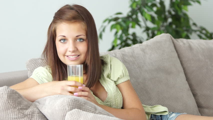 Girl resting on couch and drinking fresh juice
