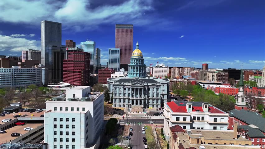 Downtown Denver Lodo cityscape sunny springtime morning blue sky Capitol Hill Civic Center Park Colorado Capitol building aerial drone golden dome skyscraper buildings car traffic city streets upwards