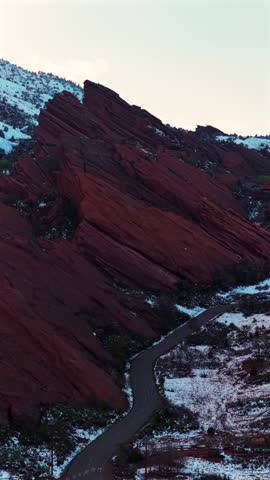 Sunset Red Rocks Park and Amphitheater spring snow-covered jagged Red Rocks music concert venue landmark Morrison Colorado aerial drone sunset Mt Morrison landscape Denver Front Range forward upwards
