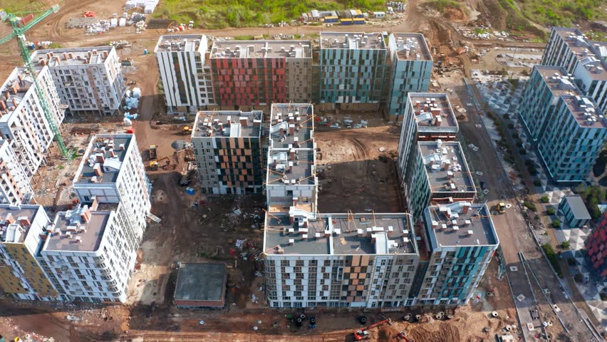 Construction activity is visible at a residential development site with tower cranes operating. New buildings are taking shape, indicating urban growth.