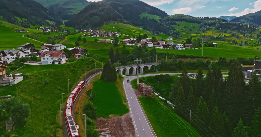 Establishing shot of Switzerland. Aerial view of the green meadows of Switzerland, with the Alps and clouds in the background