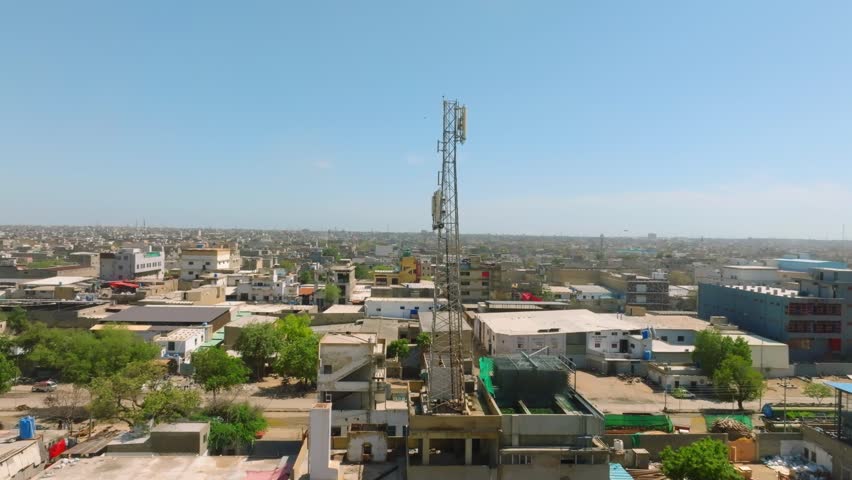 Aerial - Karachi urban skyline with tall telecom tower rising above dense industrial buildings