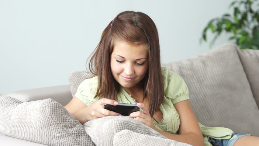 Girl resting on couch and playing games on her phone
