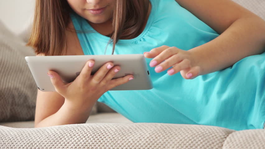 Girl lying on couch with tablet pc
