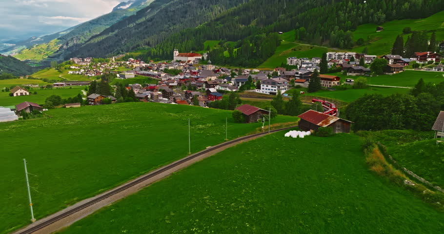 Establishing shot of Switzerland. Aerial view of the green meadows of Switzerland, with the Alps and clouds in the background