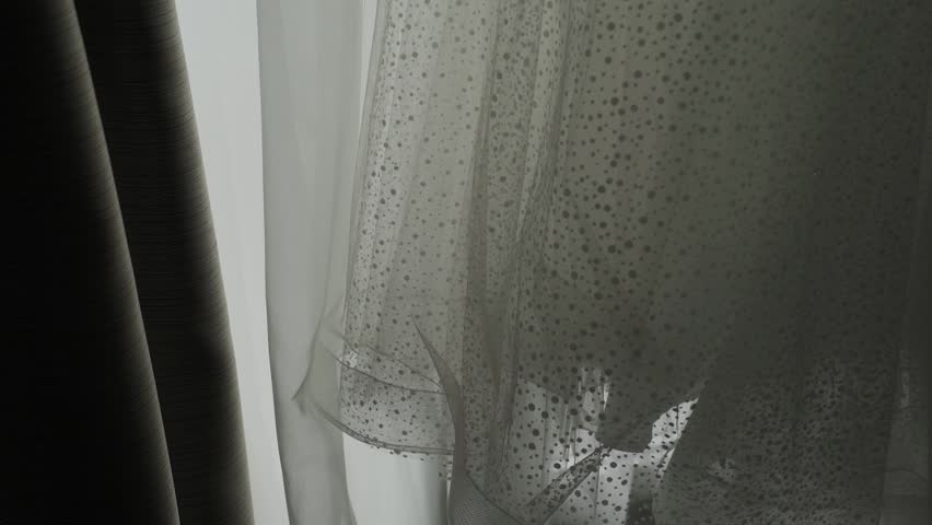 A white wedding dress hangs on the window