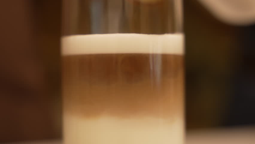 Fresh coffee mixing with milk in a transparent glass to make a delicious iced latte, fa01